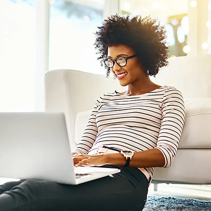 African American woman with glasses working on her laptop.