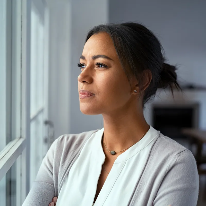 Woman looking out a window while indoors.