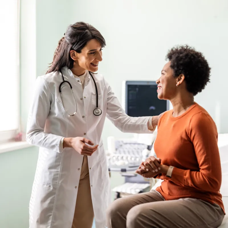 A woman talking with her doctor in an exam in room.