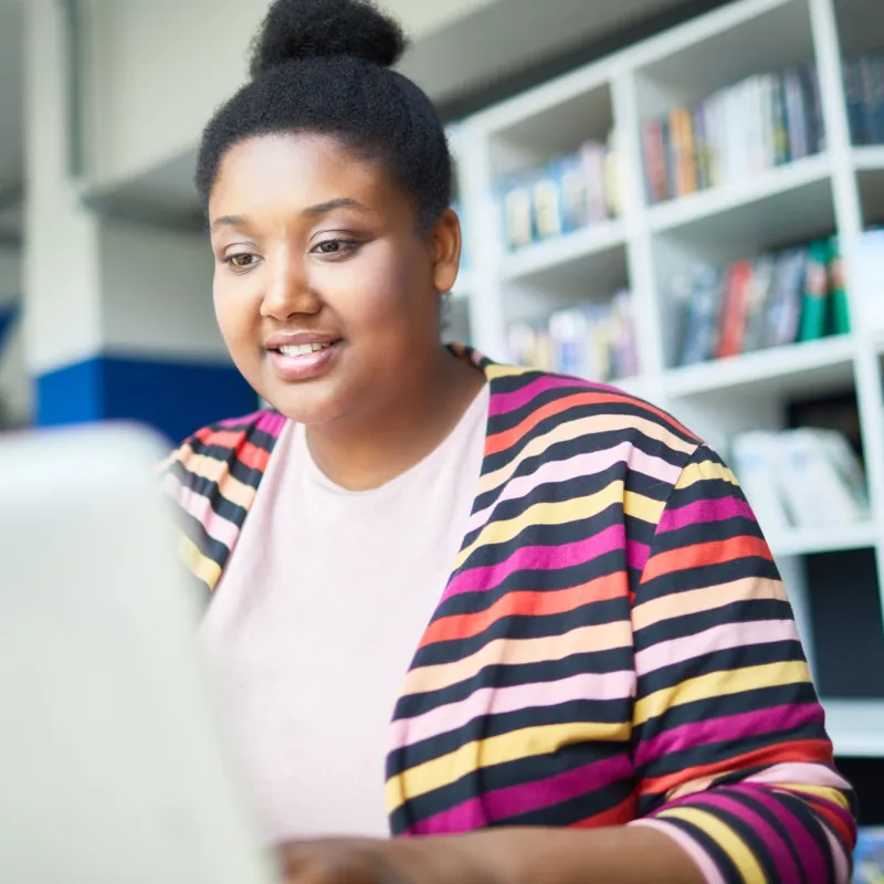 A young, female adult using her laptop while at a library