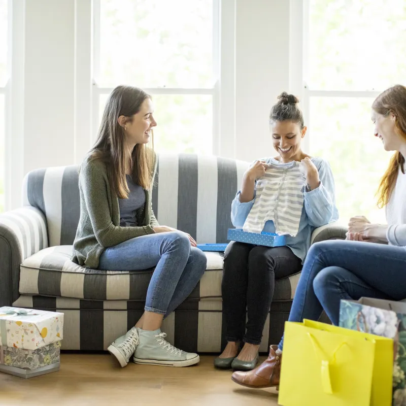 Three woman opening up gifts at a baby shower