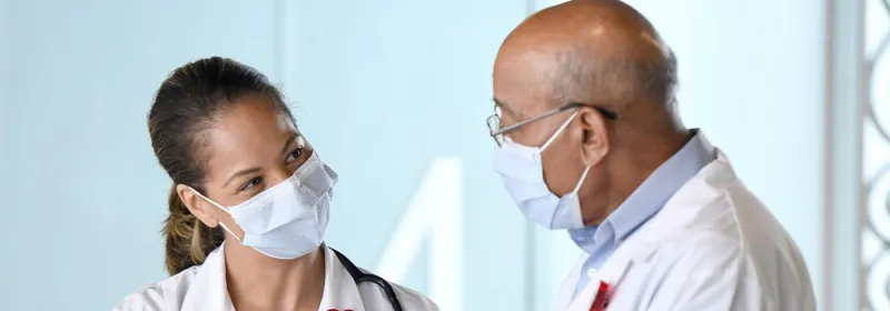 Two doctors talking while wearing masks.