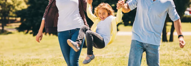 Family playing outside together in a park.