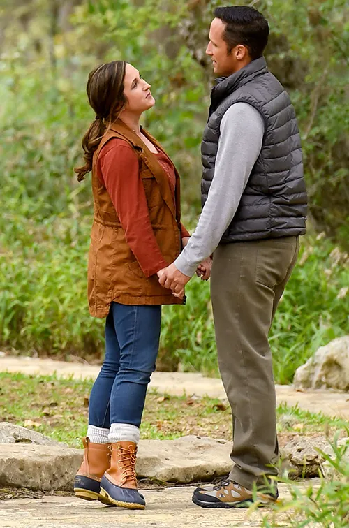 Couple standing and holding hands on a path in the forest.