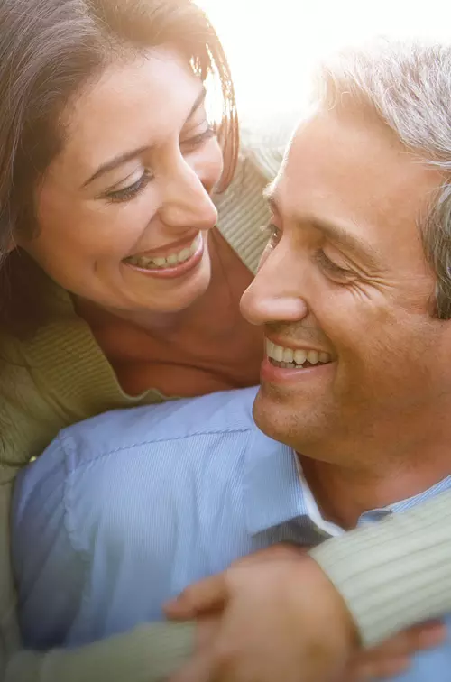 A woman hugging her husband while enjoying a walk outdoors.