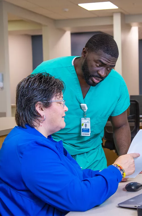 Two team members of AdventHealth Digestive Health Institute Tampa looking at a piece of paper and talking.