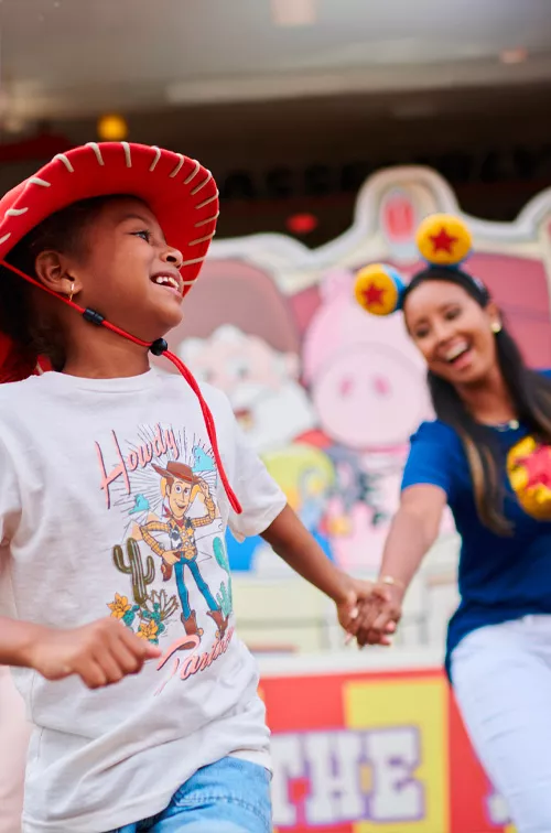 A mother holding her child's hand at a theme park.