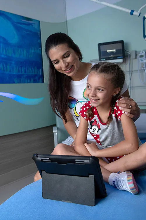 A mother and her daughter viewing a tablet device in a hospital room