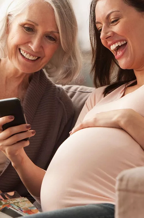 A pregnant woman with her mom looking something on her cell phone