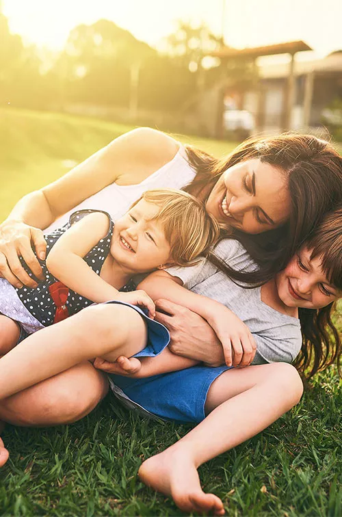 Mother playing with her children on the lawn.