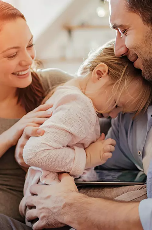 Mother and father embracing young daughter.