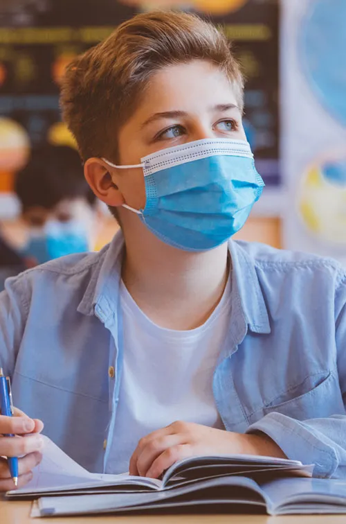 Male student wearing mask in classroom