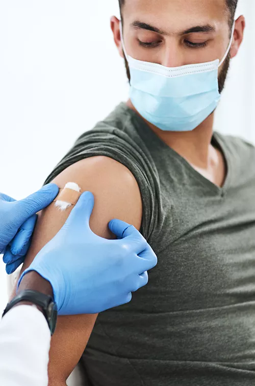 Man getting bandaged after a vaccine while wearing a mask.