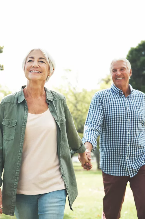 Elderly couple holding hands and walking in a park