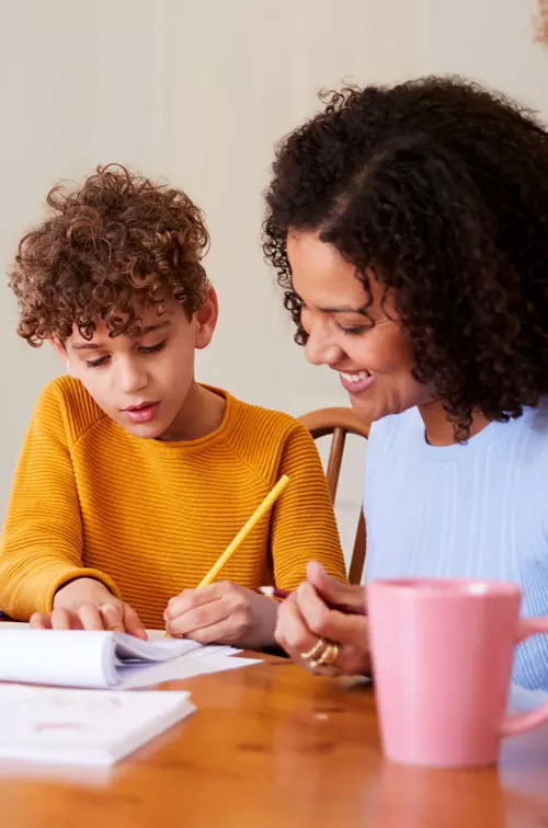 Mon and Son doing schoolwork at table