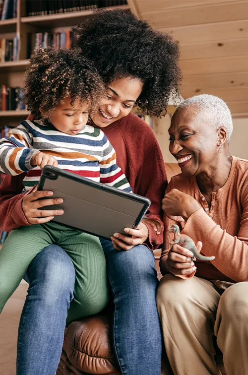 Mother, grandmother and child looking at a tablet at home.