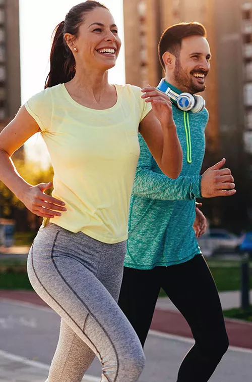 Couple running outside in the city during sunset.