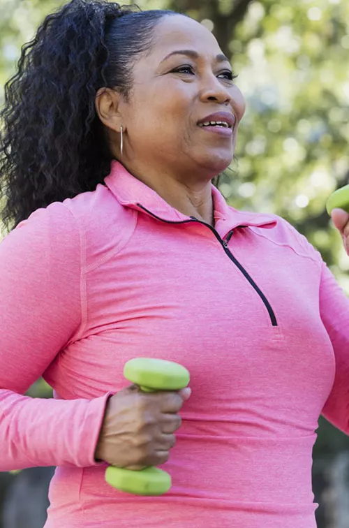 Woman walking outdoors and carrying small hand weights