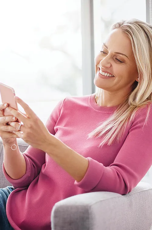 Woman sitting on a couch using a smartphone.