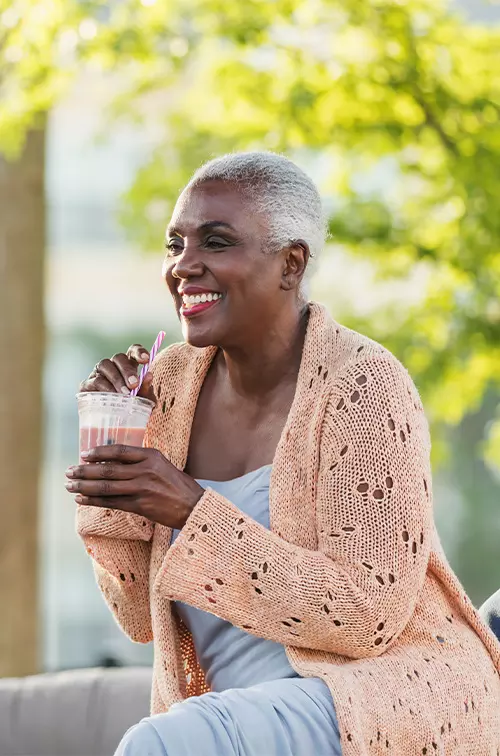 A Black Woman Enjoys a Smoothie on a Bench Outside