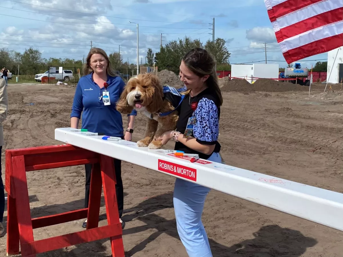 Wilbur, AdventHealth's Chief Barking Officer, "signs" the beam for the new AdventHealth Meadow Pointe ER.