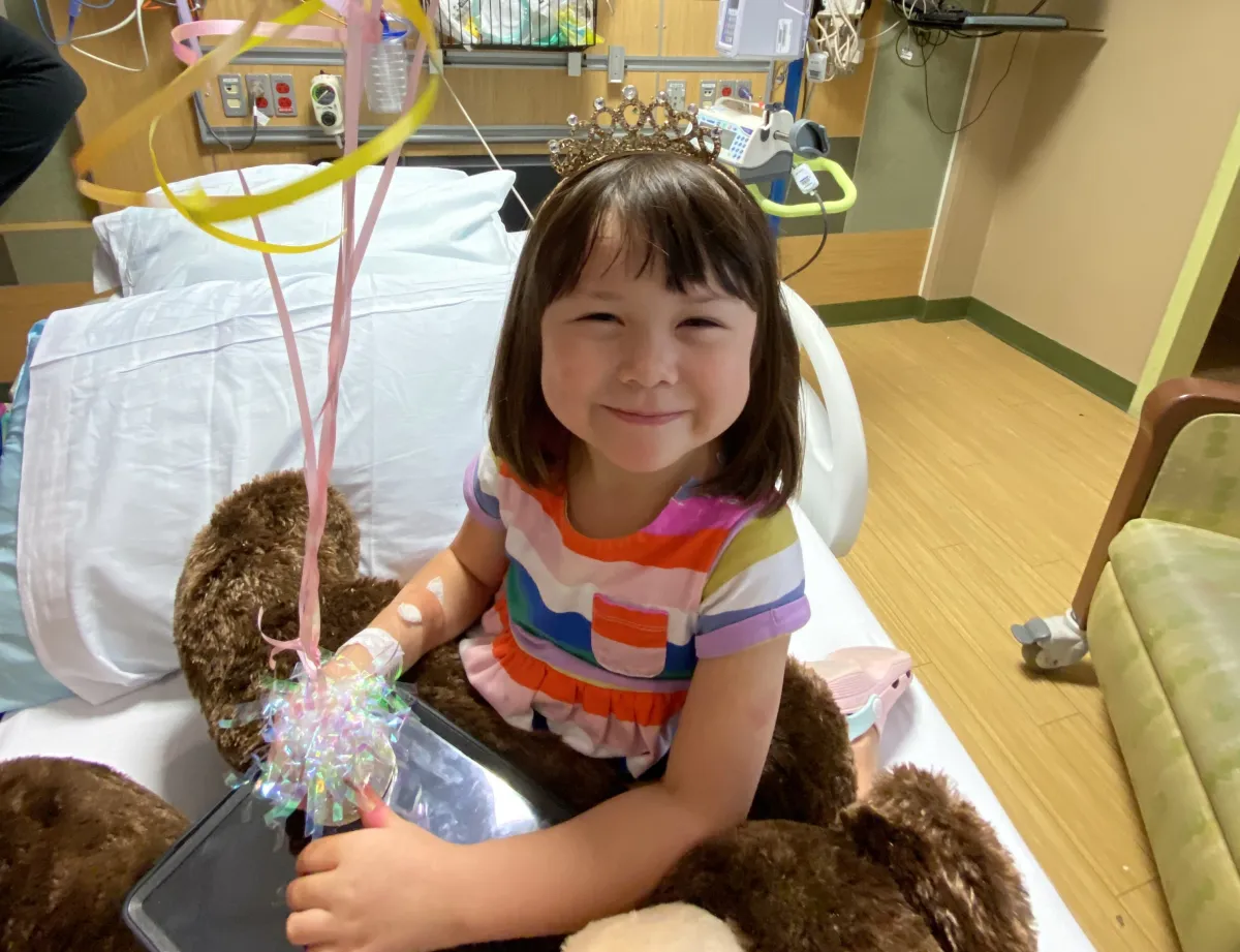 Faith Ahn smiles at the camera with balloons to celebrate leaving the hospital.