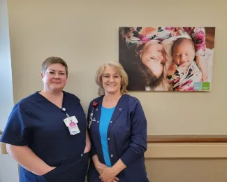 Lactation consultants stand in front of a mom with her newborn