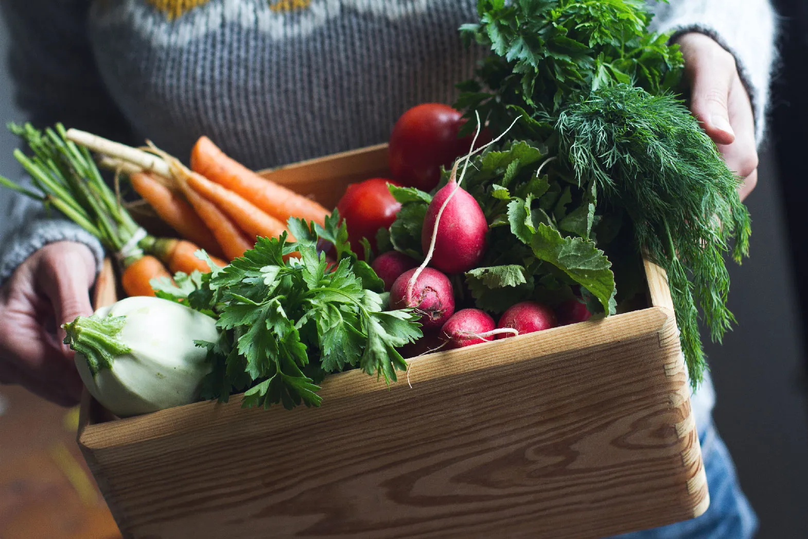 A person holding a box of vegetables