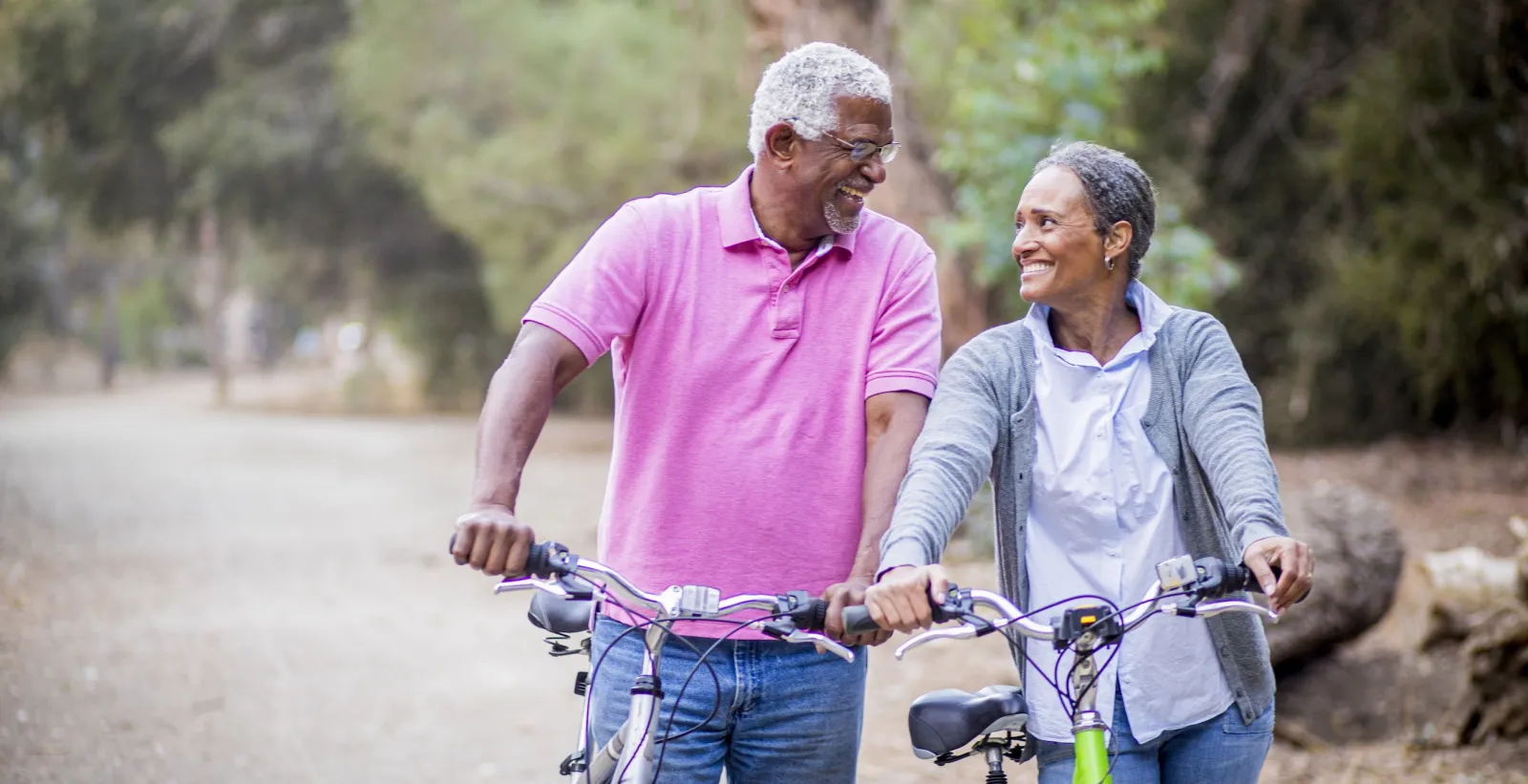 Older couple walking with bikes.